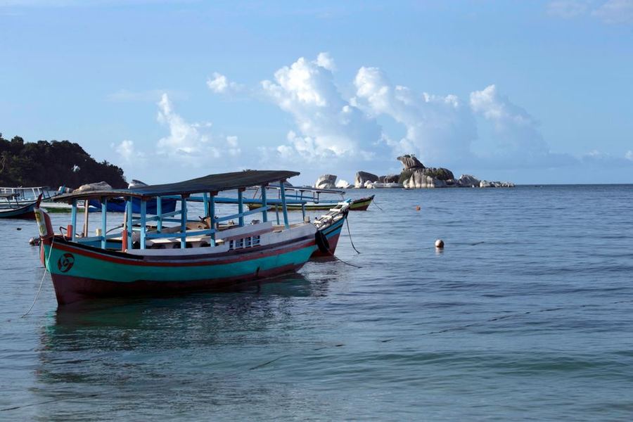 Wooden fishing boat anchored on calm water